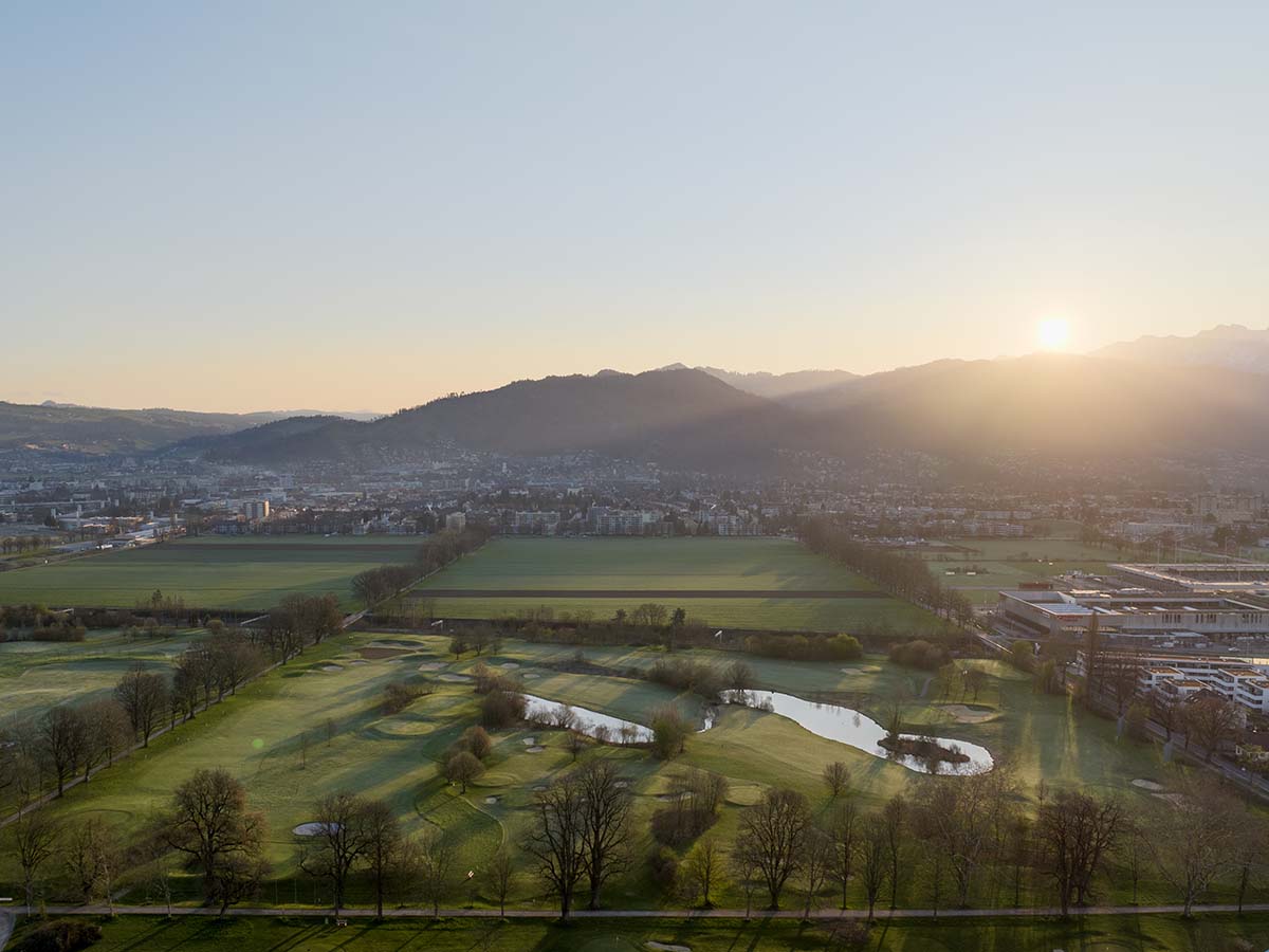 Golfplatz mit Bergen und Stadt im Hintergrund